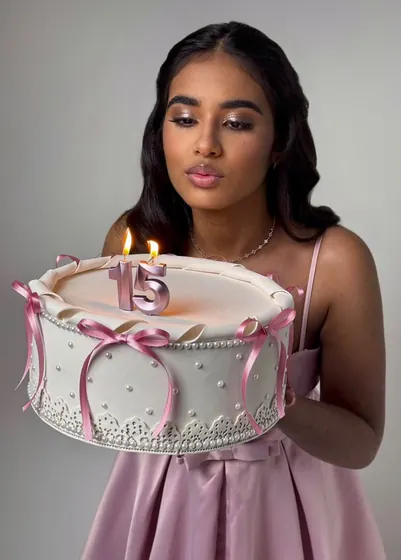 Aniversariante de 15 anos segurando bolo com velas
