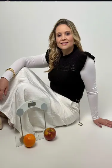 Nutricionista sentada ao lado de balança e frutas