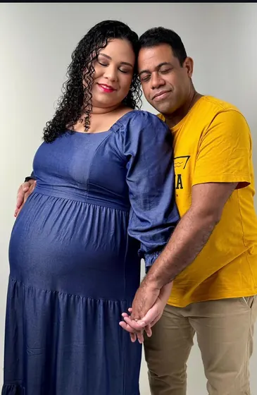 Casal grávido de mãos dadas sobre a barriga