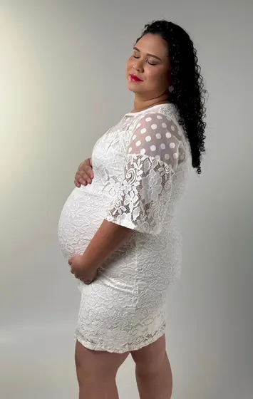 Gestante de perfil em vestido de renda branca